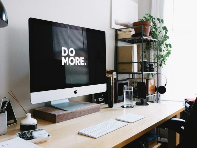 Escritorio moderno con un ordenador y el texto "DO MORE" en la pantalla.